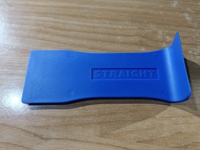 Ferramenta plástica azul com inscrição STRAIGHT sobre mesa de madeira clara