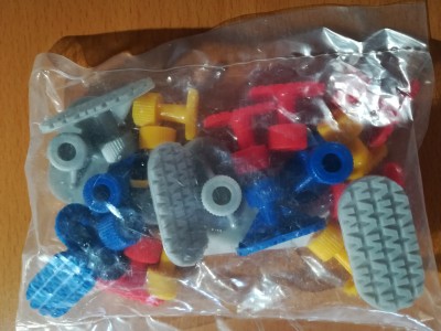 Pacote com peças de plástico coloridas para montar, sobre uma mesa de madeira.