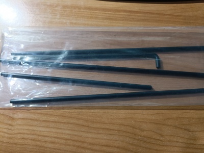 Varas metálicas pretas finas em embalagem plástica transparentes sobre madeira clara