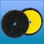 Três discos abrasivos redondos com textura esponjosa, duas pretos e um amarelo, sobre fundo azul