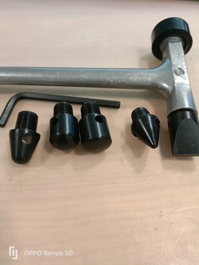 Conjunto de martelo metálico e peças roscadas pretas sobre mesa de madeira clara