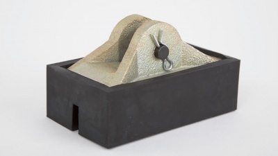 Base preta com peça metálica cinza e pino com argola