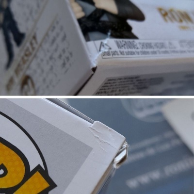 Detalhe de cantos danificados em caixas de papelão branco com texto em inglês e fundo azul e branco