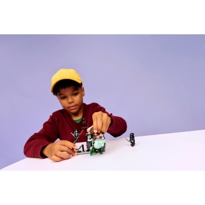 Criança a brincar com brinquedos de bonecos e veículo em fundo lilás