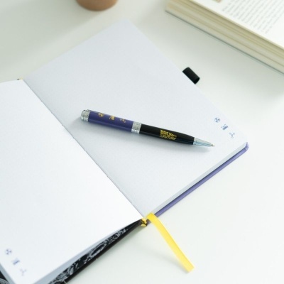 Caderno aberto com páginas pontilhadas, marcador amarelo e caneta preta e roxa com texto 'BACK TO THE FUTURE'.