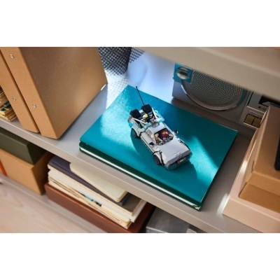 Miniatura de carro branco de brincar sobre livro azul numa prateleira com caixas de arquivo