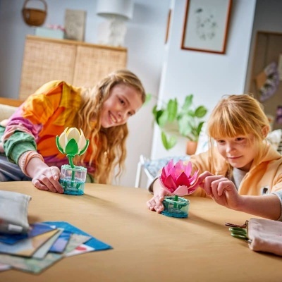 Duas crianças brincando com flores de lótus de brinquedo coloridas numa mesa em casa