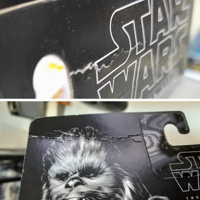 Embalagem preta de figura Star Wars com imagem de Chewbacca e texto, com rasgões visíveis