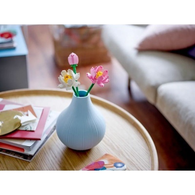 Vaso azul claro com flores de plástico sobre mesa de madeira redonda