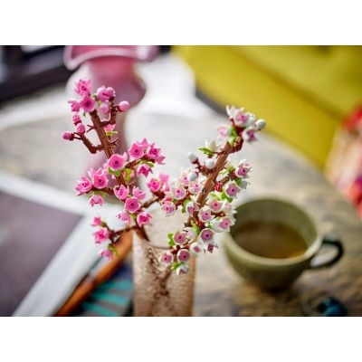 Arranjo de flores artificiais em vaso sobre mesa com chávena verde