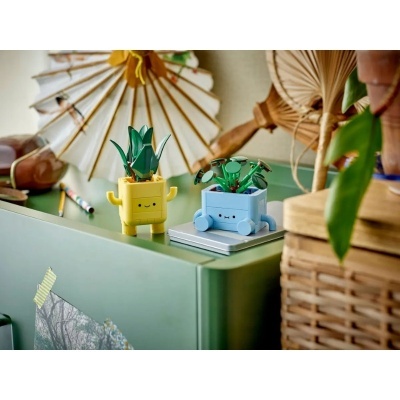 Vasos miniatura amarelo e azul com plantas artificiais e expressões faciais sorridentes