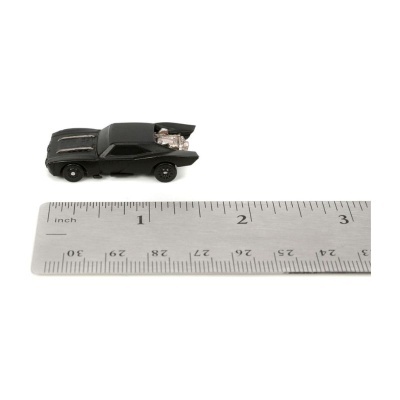 Miniatura de carro preto com motor exposto ao lado de régua metálica.