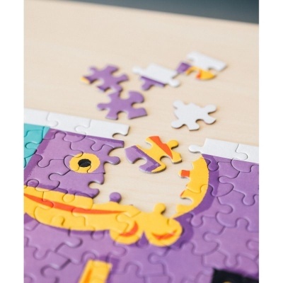 Peças de quebra-cabeças coloridas parcialmente montadas sobre uma mesa clara