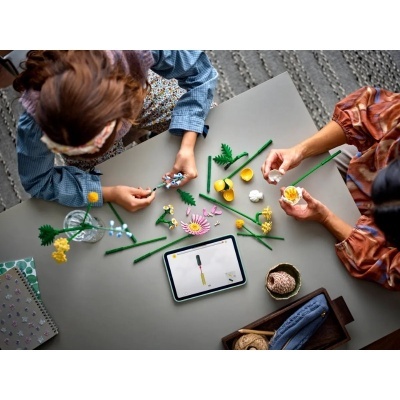 Mesa com peças plásticas de montar flores e tablet com instruções digitais