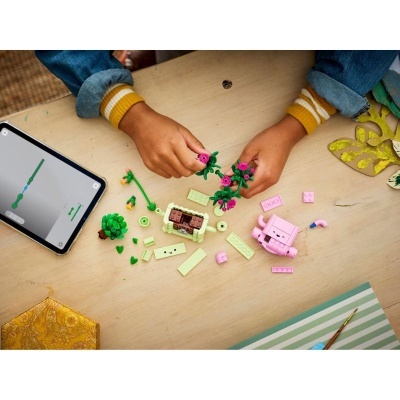 Mãos a montar brinquedo de peças tipo lego com flores e tablet com instruções