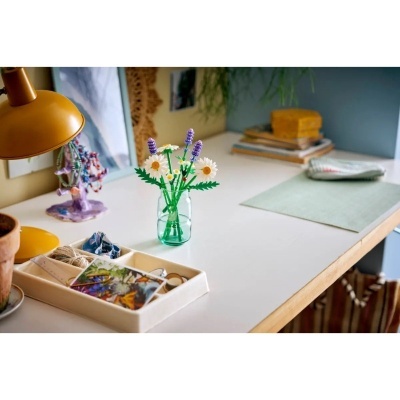 Mesa branca com arranjo de flores artificiais e candeeiro amarelo