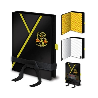 Caderno preto com detalhes amarelos e logotipo Cobra Kai, com fecho de fita preta