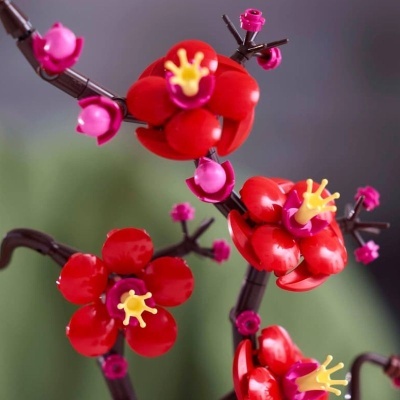 Flores artificiais vermelhas e rosas feitas de plástico montadas em ramos castanhos