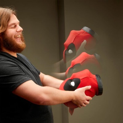 Homem segurando lata vermelha com detalhes em preto e branco num fundo cinza