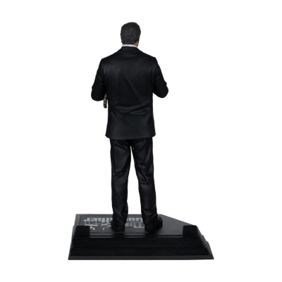 Figurina de homem de fato preto vista de costas sobre base preta.