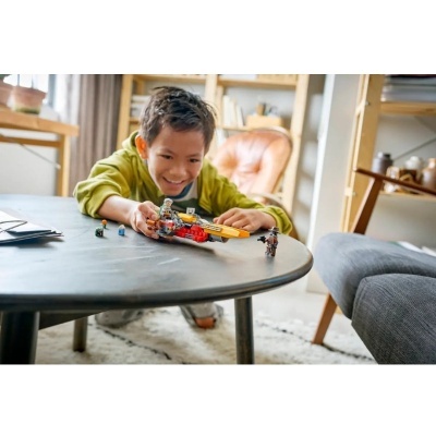 Criança a brincar com nave espacial de brinquedo colorida numa mesa preta