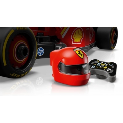 Capacete vermelho de brinquedo ao lado de volante preto e cinzento com carro Ferrari vermelho ao fundo