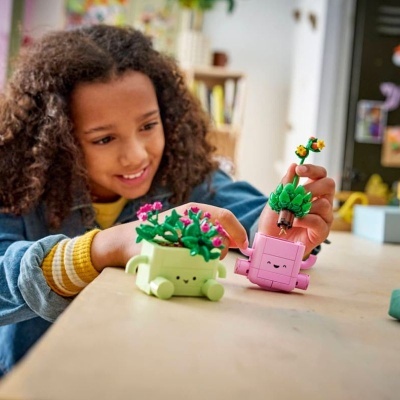 Brinquedos de construção em forma de vasos com plantas nas mãos de uma criança