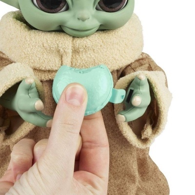 Boneco bebê alienígena verde com casaco castanho segurando objeto verde