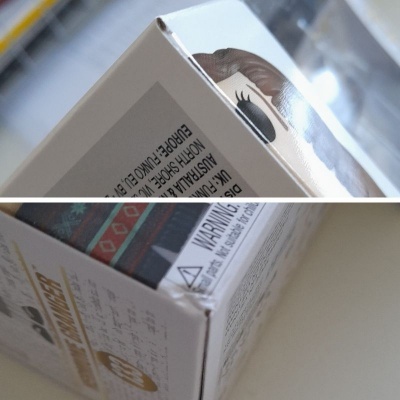 Caixa de brinquedo de papel/cartão com texto de aviso e figura colorida visível.