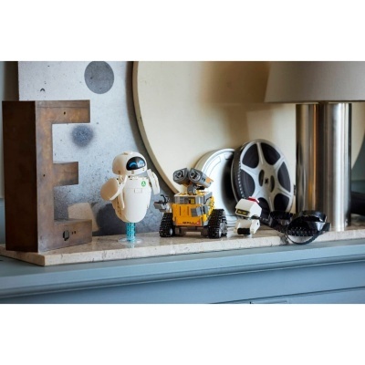 Figuras de robôs em miniatura numa prateleira com uma letra E metálica e bobina de filme