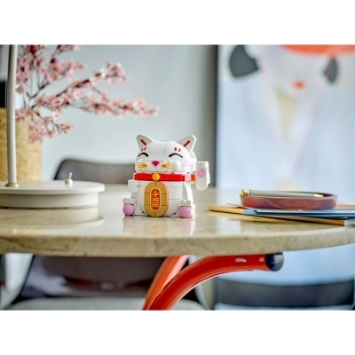 Figura de gato da sorte feito de blocos de montagem em branco, vermelho e rosa sobre mesa clara