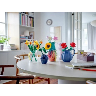 Vasos com flores artificiais coloridas sobre mesa branca numa sala moderna