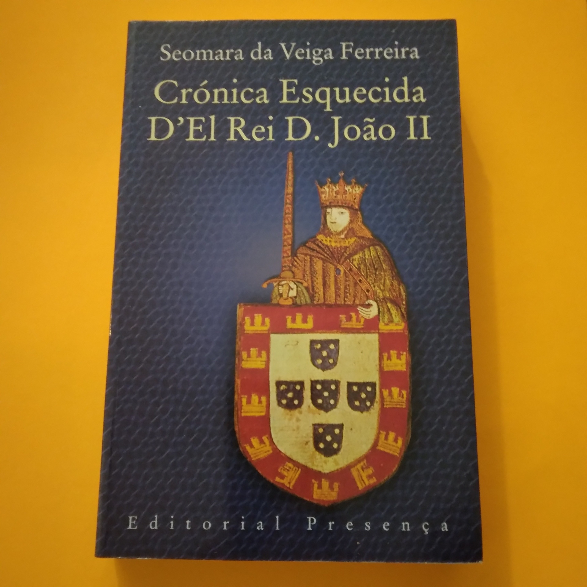 Crónica Esquecida D'El Rei D. João II, Seomara da Veiga Ferreira Capa de livro azul escura com figura de rei medieval e escudo, texto do título e autor.