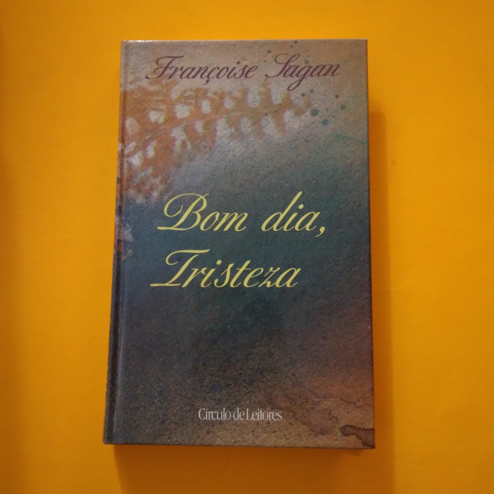 Bom Dia, Tristeza, Françoise Sagan Livro 'Bom dia, Tristeza' com capa azul e castanha sobre fundo amarelo