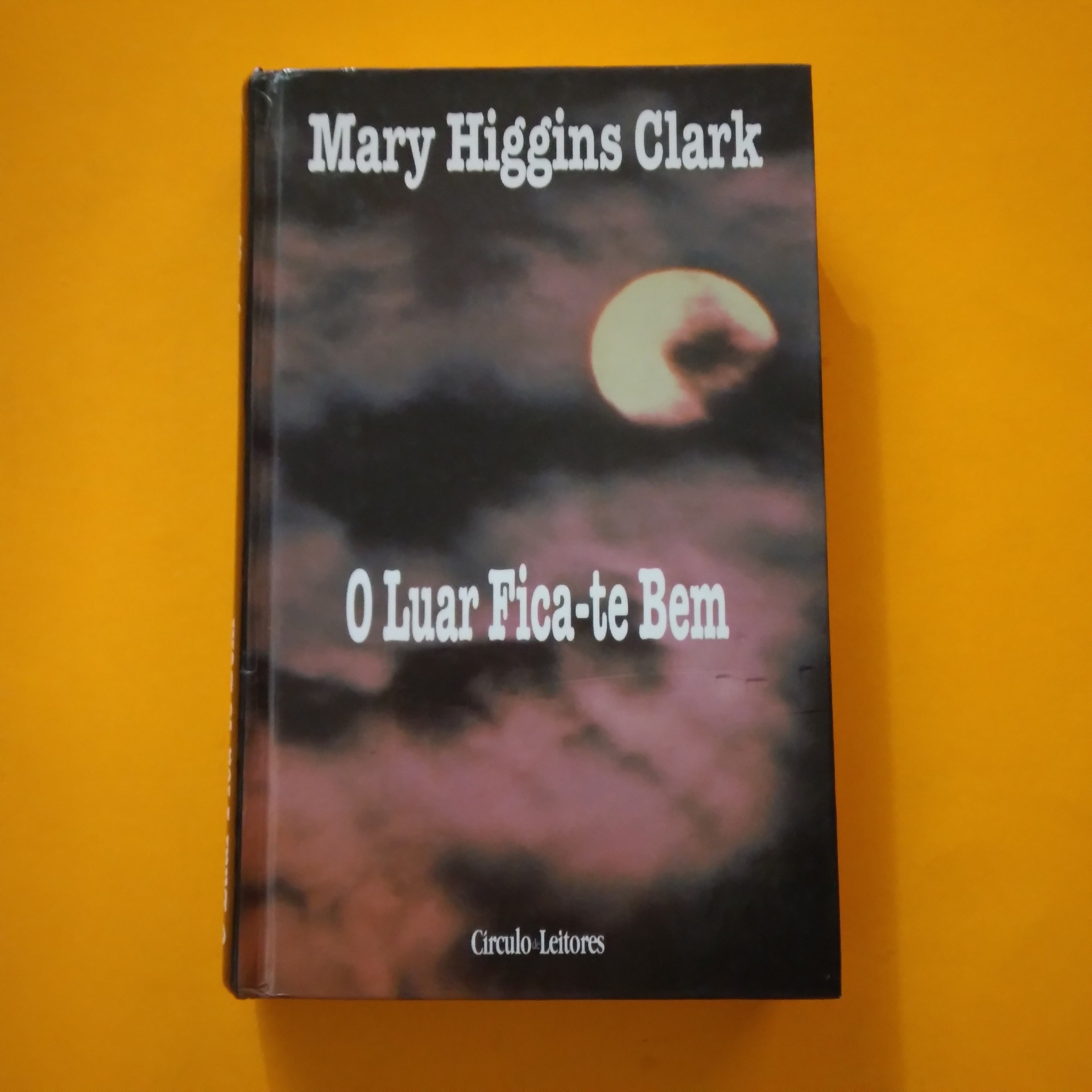 O Luar Fica-te Bem, Mary Higgins Clark Capa de livro com título O Luar Fica-te Bem e imagem de lua cheia no céu nublado