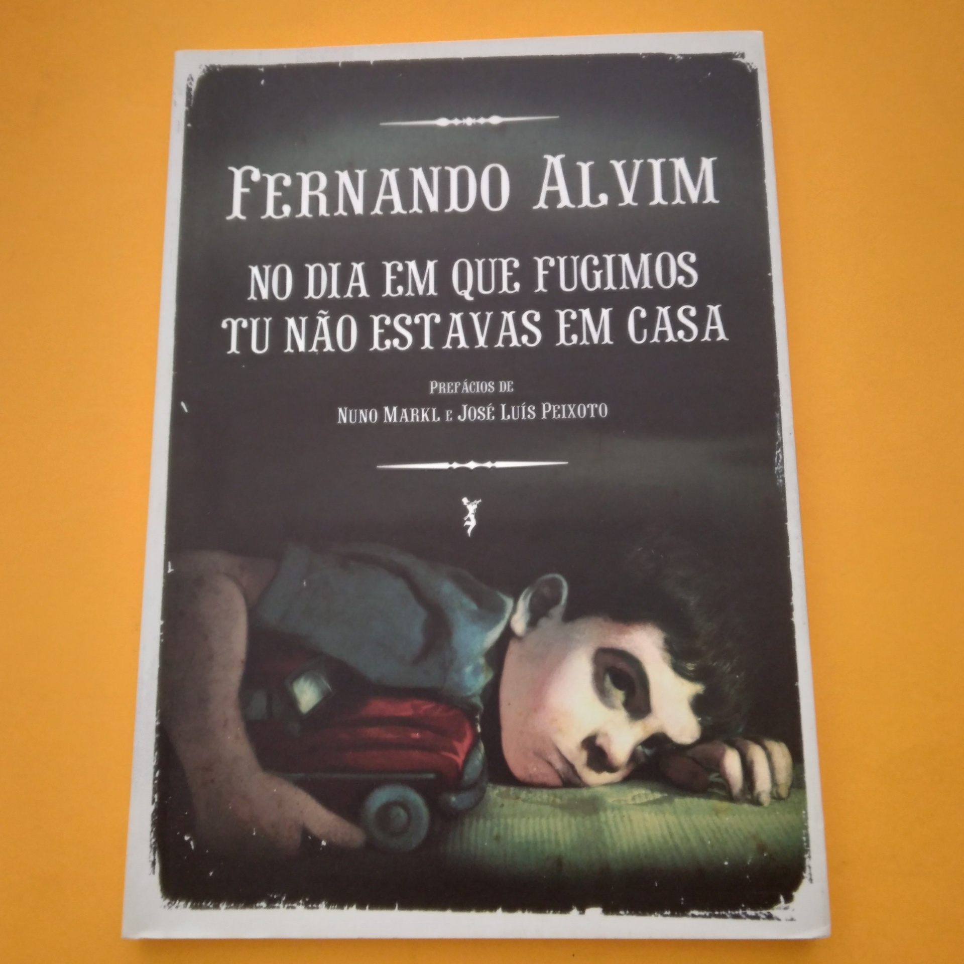 No Dia em que Fugimos Tu Não Estavas em Casa, Fernando Alvim Capa de livro preto com ilustração de rapaz e carrinho, texto branco