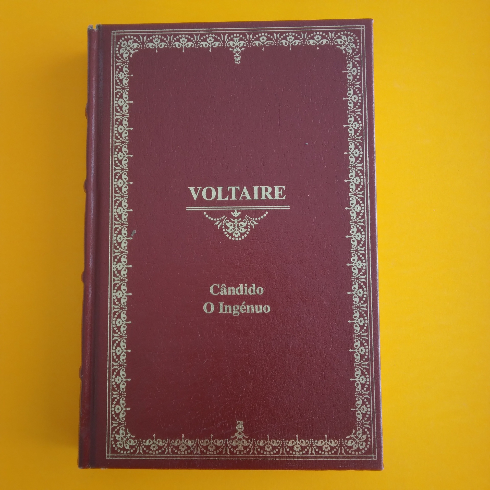 Cândido / O Ingénuo, Voltaire Livro vermelho vinho capa dura com texto dourado 'VOLTAIRE Cândido O Ingénuo'