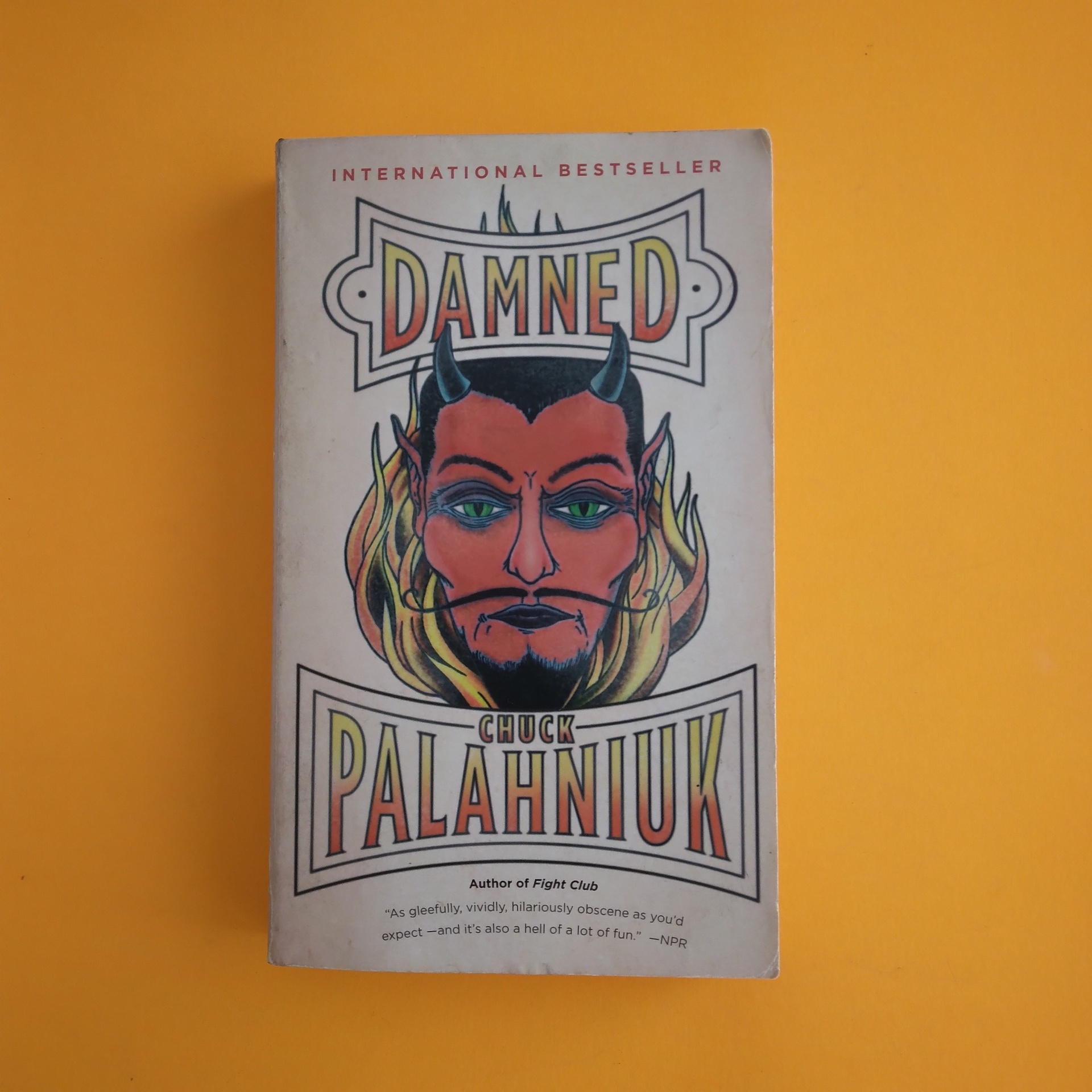 Damned, Chuck Palahniuk Livro 'Damned' de Chuck Palahniuk com capa ilustrada em fundo laranja