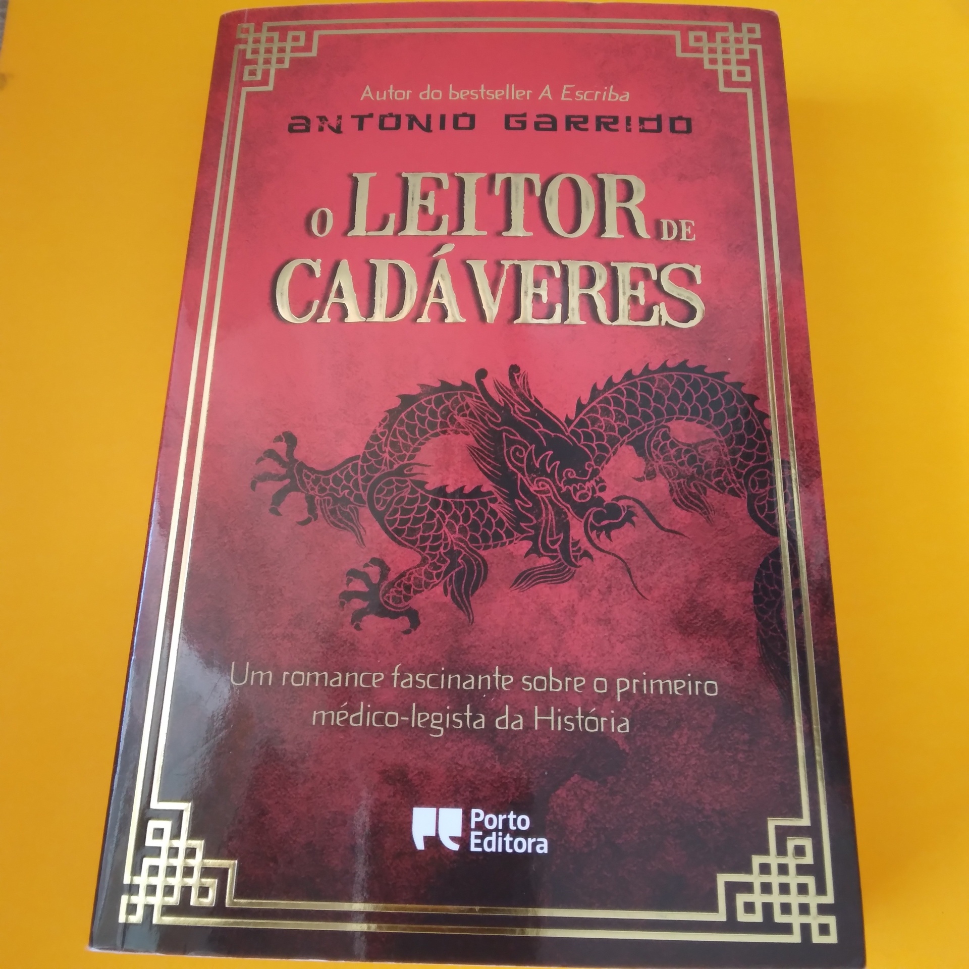 O Leitor de Cadáveres, António Garrido Capa de livro vermelho com dragão e texto em dourado e branco