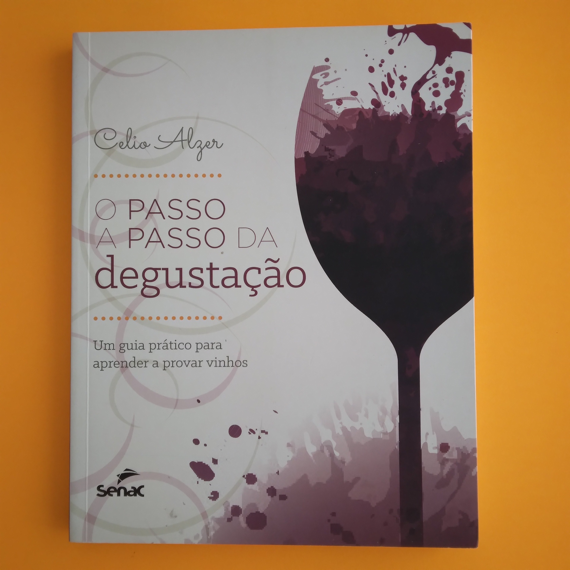 O Passo a Passo da Degustação, Celio Alzer Capa do livro O Passo a Passo da Degustação com copo de vinho e respingos