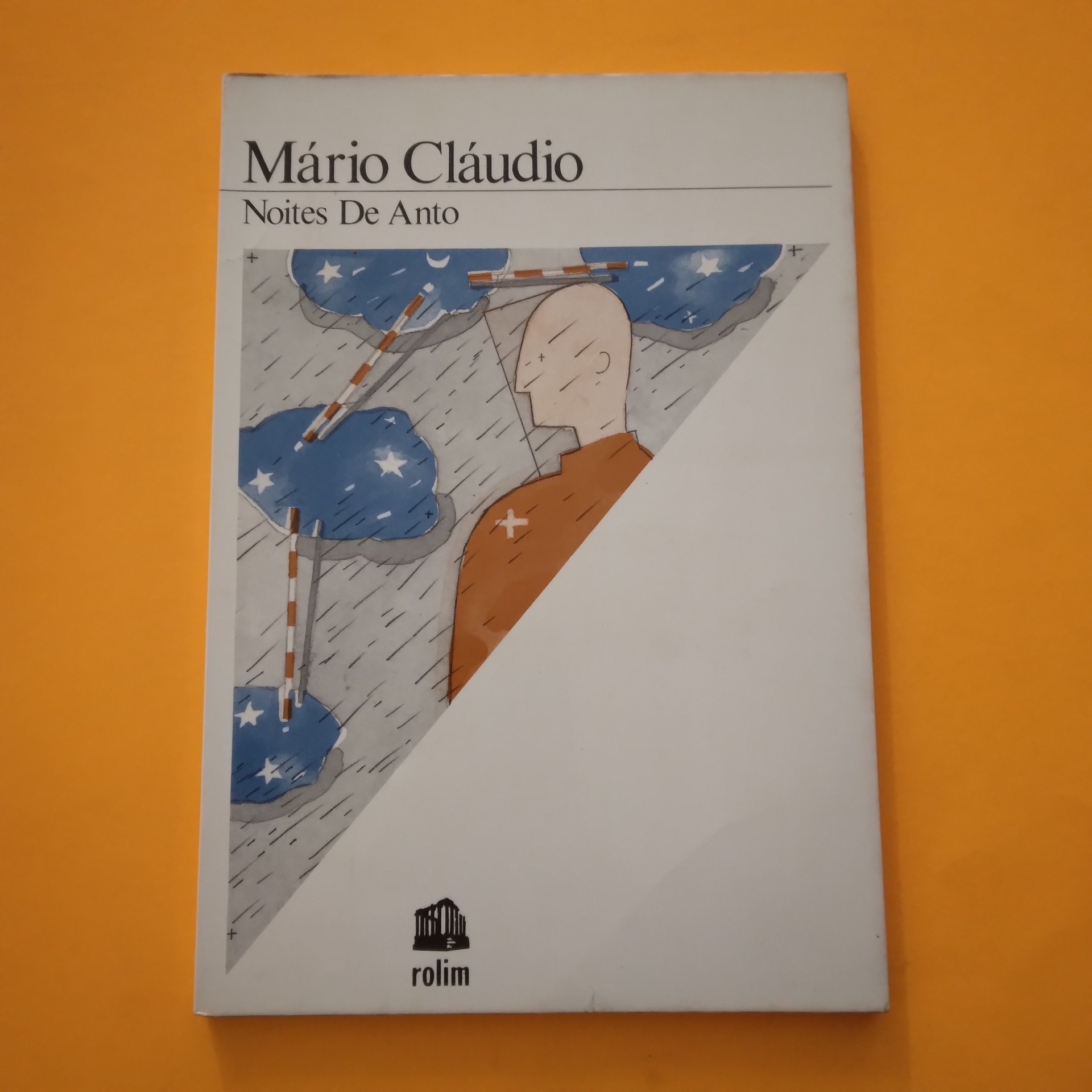 Noites de Anto, Mário Cláudio Capa de livro branco com ilustração triangular de figura humana e nuvens azuis com estrelas