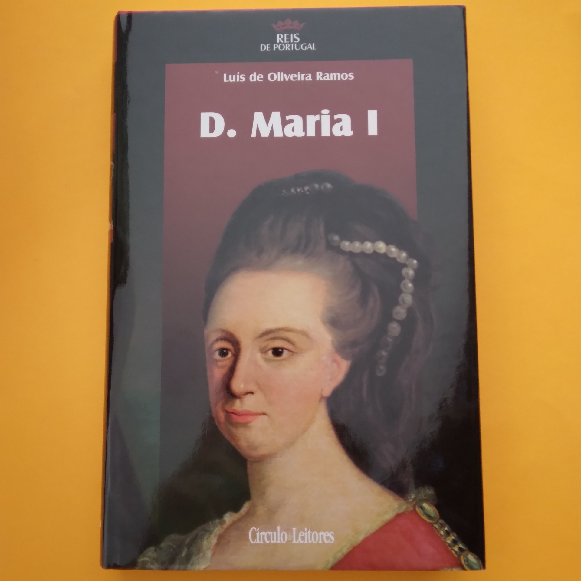 D. Maria I, Luís de Oliveira Ramos Livro 'D. Maria I' com retrato histórico e fundo preto e vermelho sobre superfície amarela