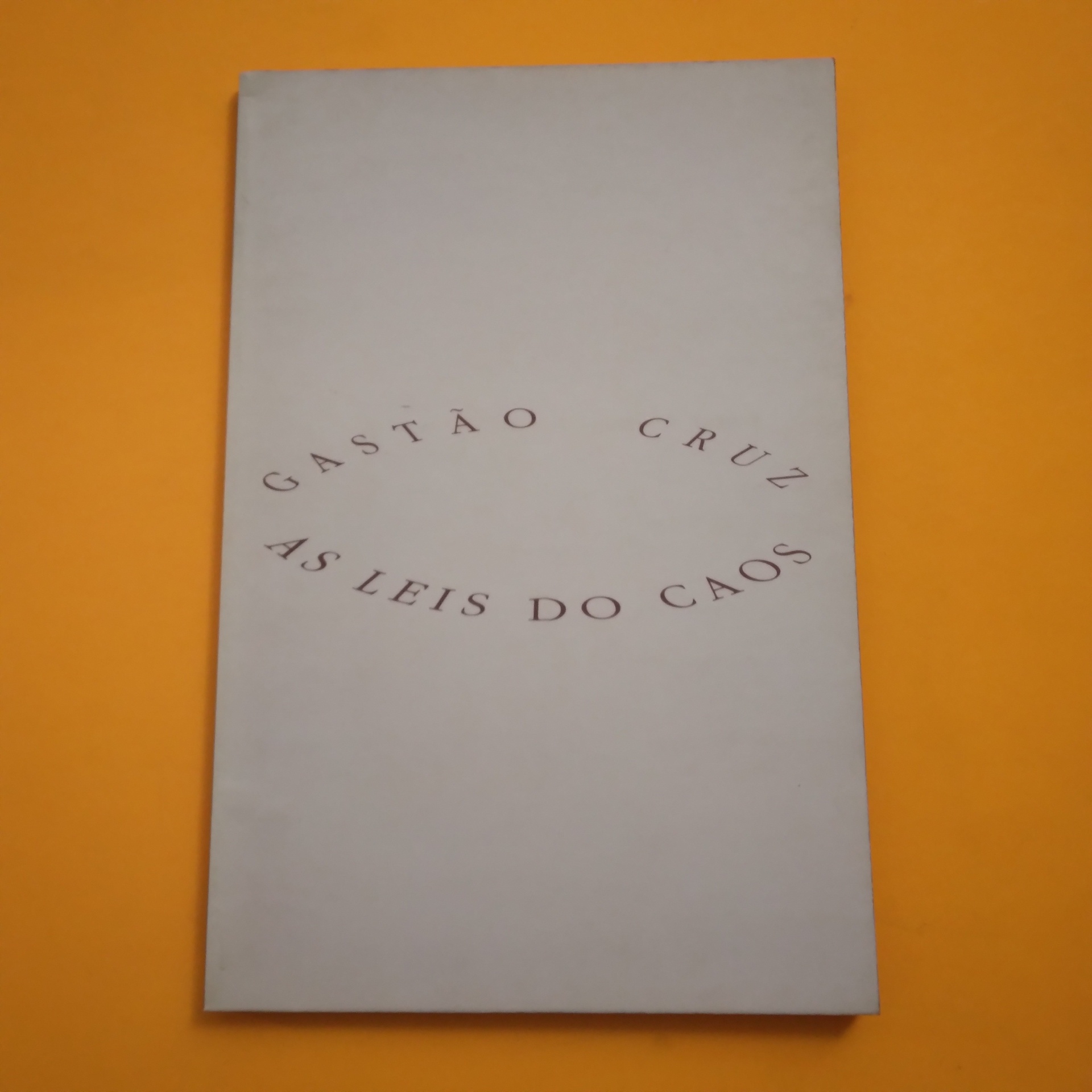 As Leis do Caos, Gastão Cruz Livro branco com texto GASTÃO CRUZ AS LEIS DO CAOS em fundo laranja