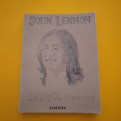Livro de John Lennon com desenho e texto na capa, fundo amarelo