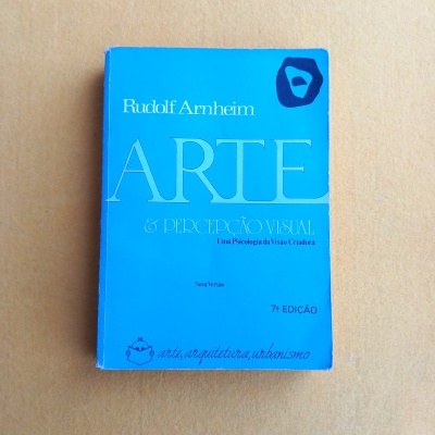 Livro azul de arte e percepção visual de Rudolf Arnheim sobre fundo liso