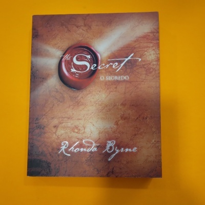 Livro The Secret O SEGREDO de Rhonda Byrne em fundo amarelo