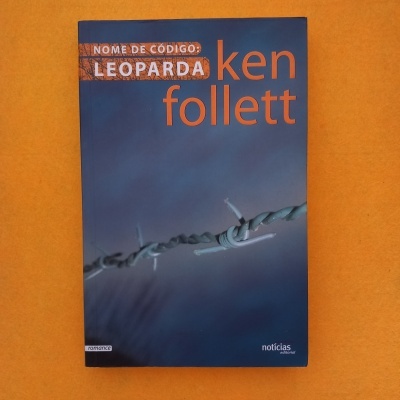 Livro com capa azul com arame farpado e texto laranja e branco