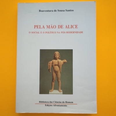 Capa de livro branca com texto vermelho e preto e escultura ao centro sobre fundo amarelo