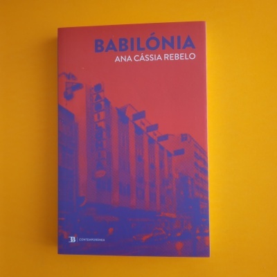 Capa de livro vermelha com ilustração de edifícios em azul e título BABILÓNIA