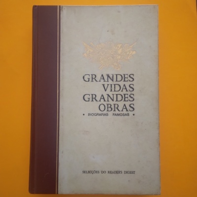 Livro capas duras bege e castanho com título Grandes Vidas Grandes Obras sobre fundo amarelo